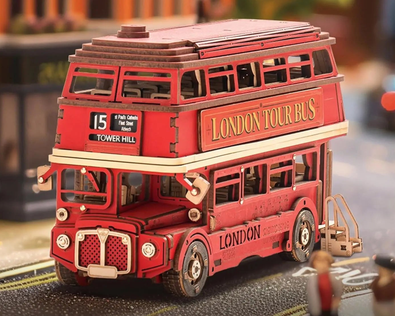Red double-decker toy bus with 'London Tour Bus' text on a blurred street background.