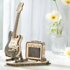 Metallic model of a guitar and amplifier with a gift box and flowers on a light background