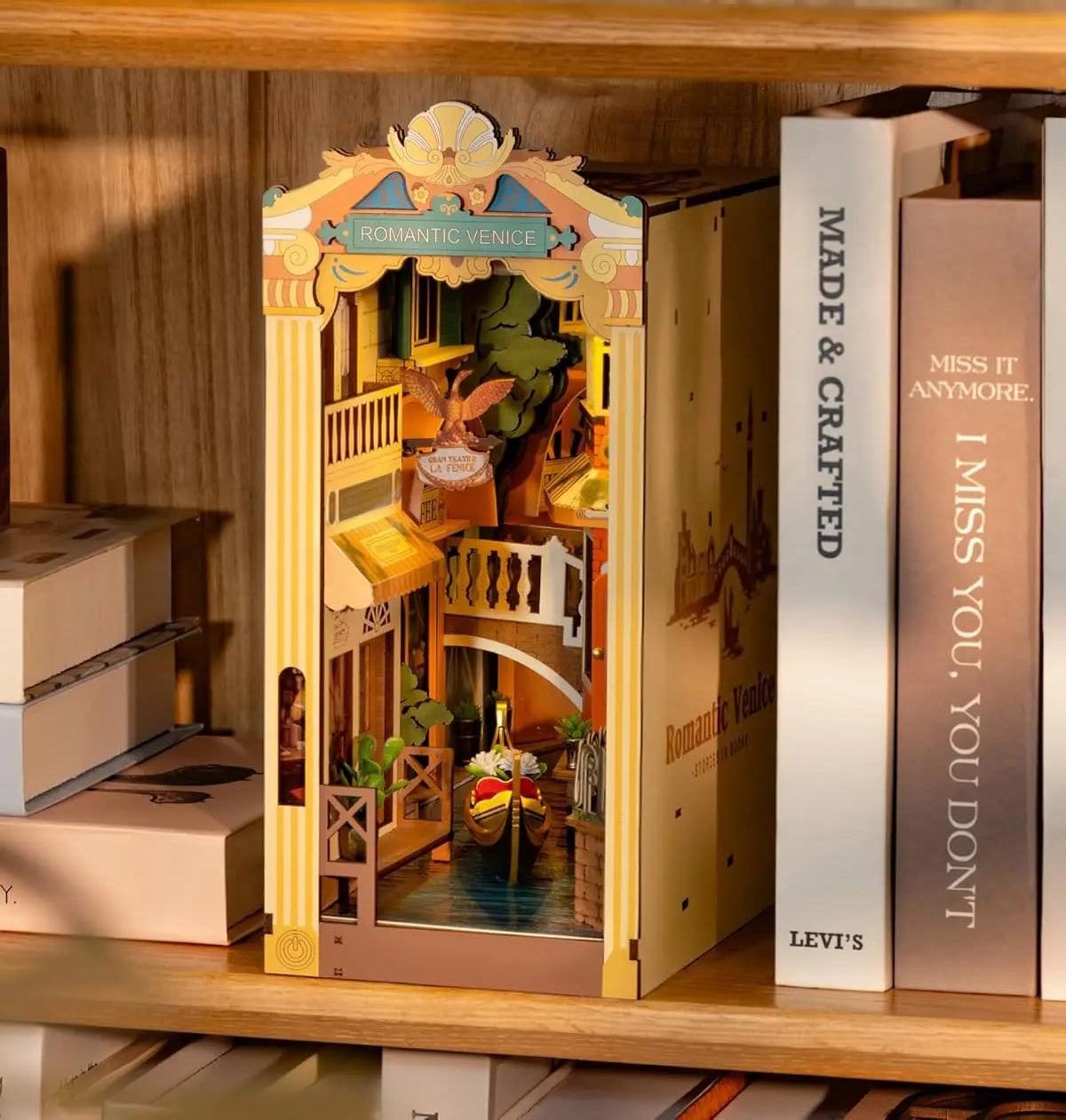 Model of a floating city between books with 'Romantic Venice' branding on a wooden shelf.