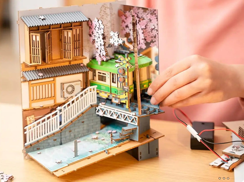 Step-by-step booklet for building a model train set with a person working on it.
